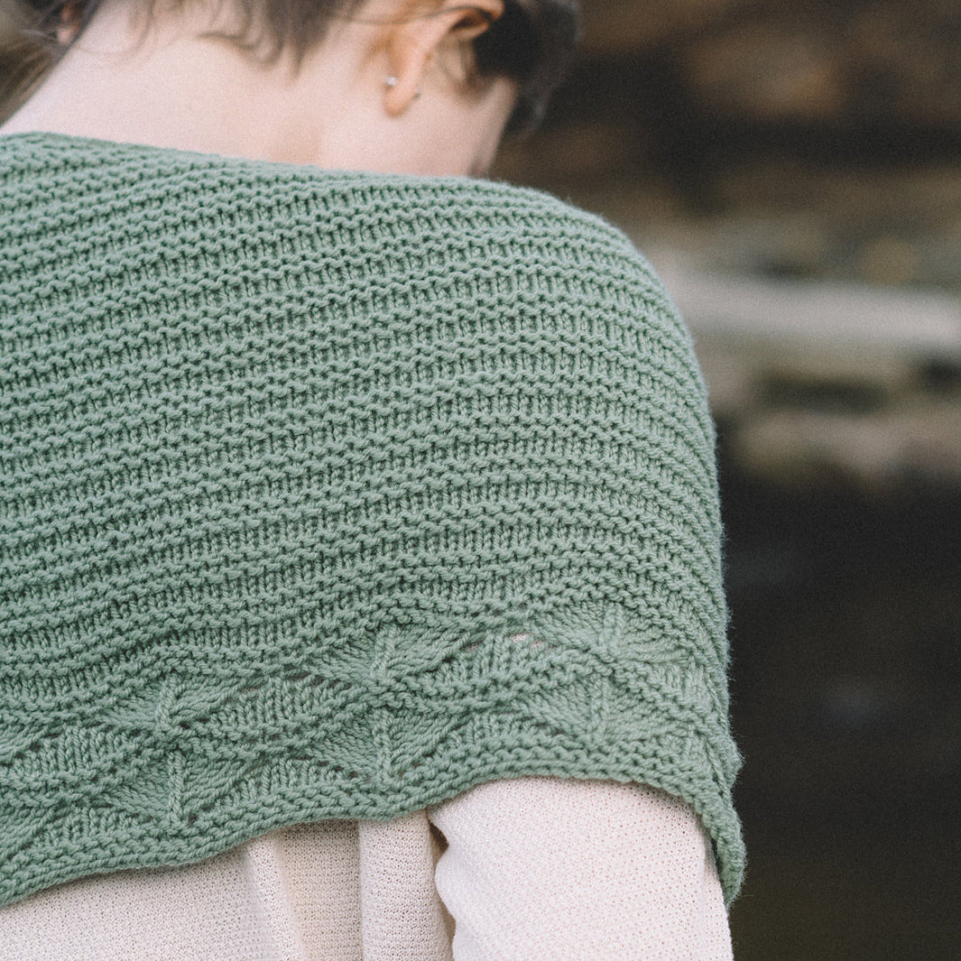 Close-up of the Cave Point shawl’s garter stitch body and leaf lace border, knit in green Quince & Co. Chickadee