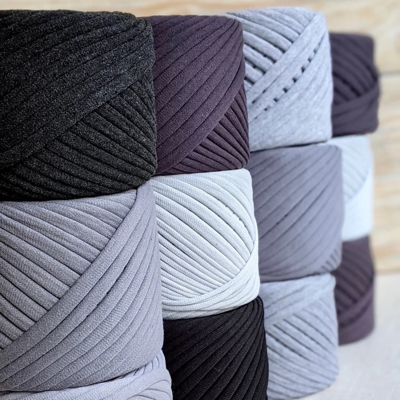 Image show 8 black cakes of Bobilon Medium Yarn ranging in colors of black and grays.