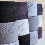 Image show 8 black cakes of Bobilon Medium Yarn ranging in colors of black and grays.