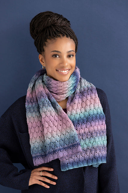 Woman wearing the Adalynn lace scarf looped around her neck, knit in Ella Rae Color Magic Pretty in Pink (510)
