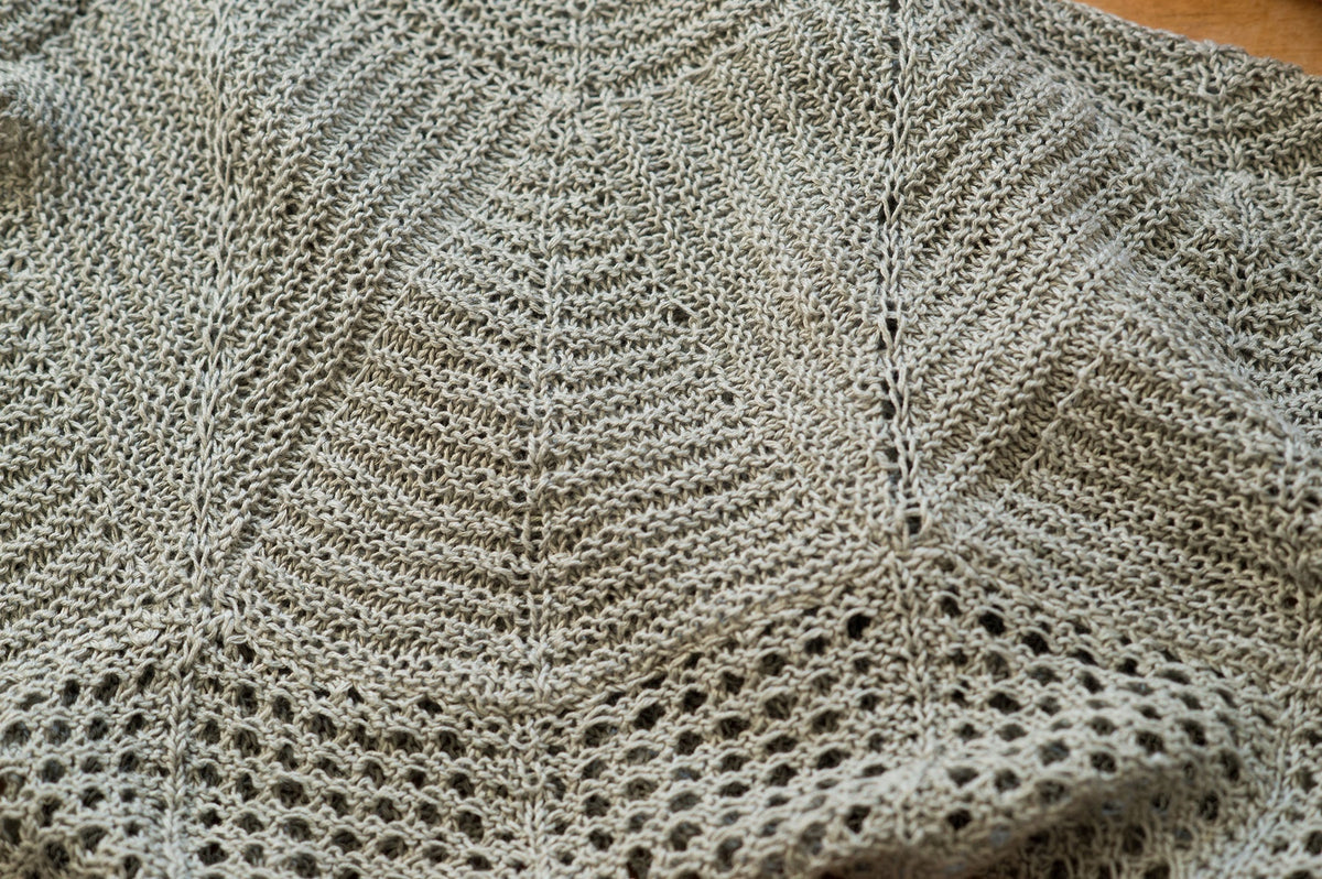 Detail of Villa shawl by Quince & Co. showing garter wedges divided by spine stitches and a mesh eyelet edge