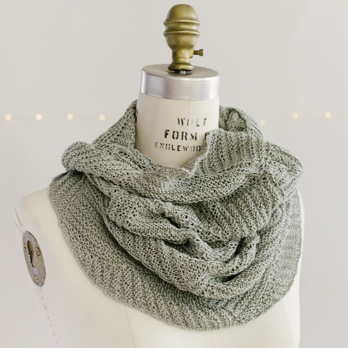 Villa Cowl by Quince & Co. in sage green, wrapped around a dress form neck as a cowl